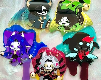 May include: A collection of colorful acrylic charms featuring cartoon characters with unique designs. Each charm has a distinct shape and color scheme, including blue, purple, green, red, and yellow. The charms have a glossy finish and are likely for decorative purposes.