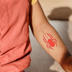 Puede incluir: Un tatuaje temporal de una araña roja en el brazo de una persona.