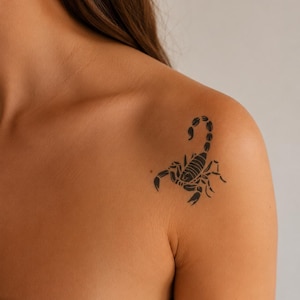 Puede incluir: Un tatuaje temporal negro que presenta un diseño detallado de escorpión con una cola curva y pinzas, aplicado sobre la piel de un hombro. El escorpión está representado en un estilo de tinta negra sólida con segmentos visibles en el cuerpo.