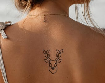 May include: A temporary tattoo featuring a black line art illustration of a deer head with stylized antlers. The design is centered on the upper back, showcasing clean, geometric lines that form the shape of the animal's face and branching antlers.