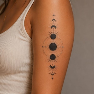 May include: A black ink tattoo on an upper arm featuring a vertical alignment of moon phases. The design includes a central full moon surrounded by geometric lines, radiating sunburst patterns, and small star symbols arranged in a symmetrical sequence.