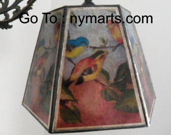 May include: A hexagonal lampshade with a floral design featuring birds. The lampshade is made of paper and has a black border. The text "Go To: nymarts.com" is printed on the lampshade.