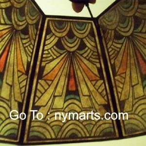 May include: A vintage lampshade with a geometric design in shades of brown, orange, green, and blue. The lampshade has a scalloped edge and features the text "Go To: nymarts.com".