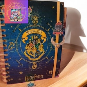 May include: A blue and gold Harry Potter notebook with a spiral binding. The cover features the Hogwarts crest and the words "Hogwarts" and "Harry Potter".