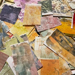 May include: A collection of textured paper pieces in various colors and patterns. The assortment includes squares and rectangles with designs like floral, geometric, and abstract shapes. Colors range from deep purple to warm orange and yellow.