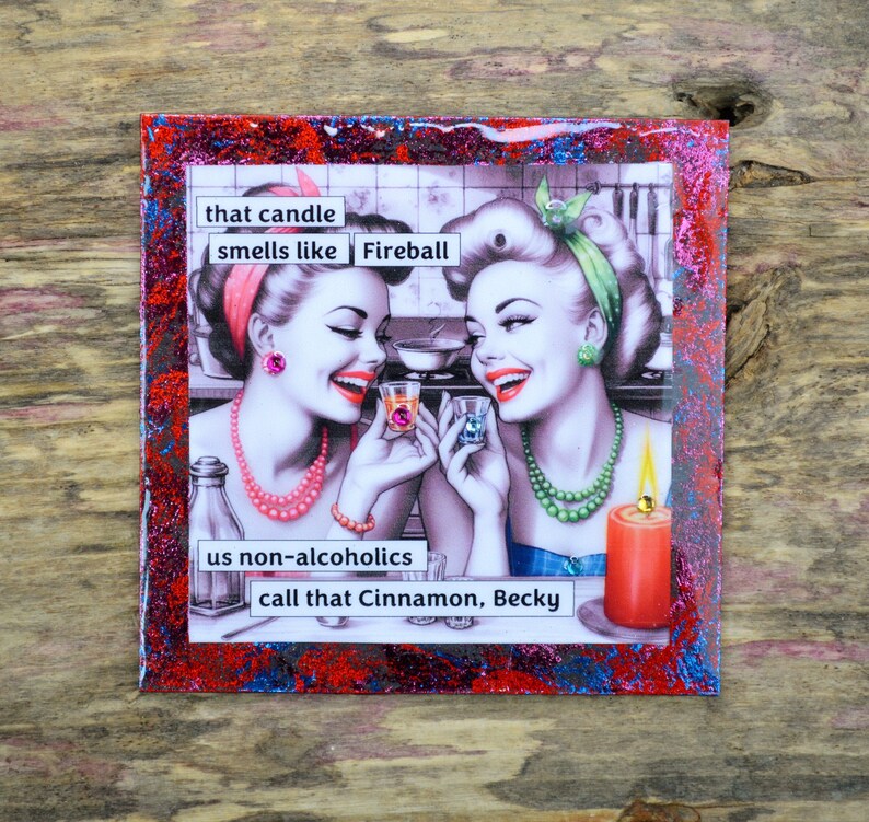 Pode incluir: Um descanso de copo vermelho, branco e azul com glitter, com uma ilustra&ccedil;&atilde;o vintage de duas mulheres segurando copos de shot. O texto no descanso de copo diz "that candle smells like Fireball us non-alcoholics call that Cinnamon, Becky".