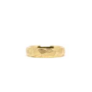 Könnte beinhalten: Ein goldener Bandring mit einer strukturierten, gehämmerten Oberfläche.