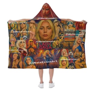 Peut inclure: Une couverture &agrave; capuche avec un motif Lady Gaga. La couverture pr&eacute;sente un collage d'images de la chanteuse, comprenant des portraits et des photos de ses performances. Le texte "LADY GAGA" et "CHROMATICA" sont visibles. La palette de couleurs comprend de l'or, du bleu et du rouge.