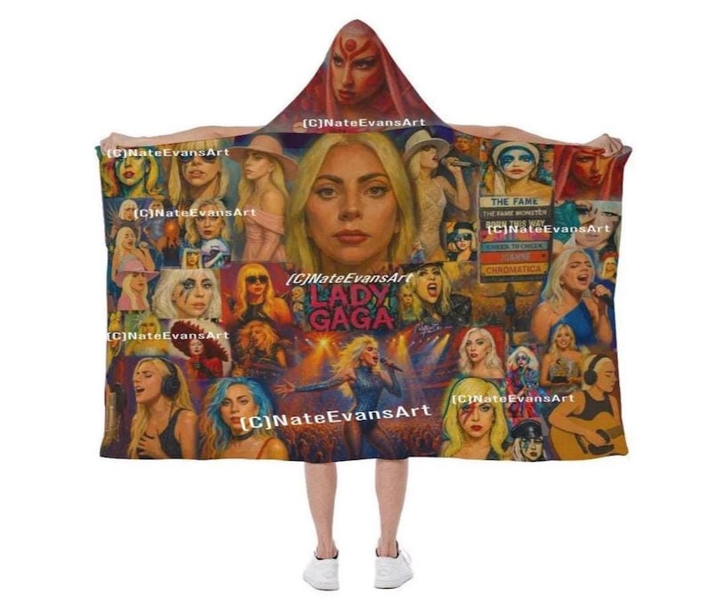 Peut inclure: Une couverture &agrave; capuche avec un motif Lady Gaga. La couverture pr&eacute;sente un collage d'images de la chanteuse, comprenant des portraits et des photos de ses performances. Le texte "LADY GAGA" et "CHROMATICA" sont visibles. La palette de couleurs comprend de l'or, du bleu et du rouge.