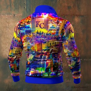 May include: A vibrant, colorful zip-up hoodie featuring a cityscape design with the letters "KC" prominently displayed. The design incorporates a variety of colors, including blue, yellow, and purple. The hoodie has a blue collar, cuffs, and waistband.