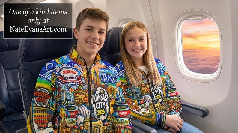 Puede incluir: Dos personas con chaquetas con cremallera coloridas con dise&ntilde;os tem&aacute;ticos de la ciudad, incluido el texto "Kansas City 2026". Las chaquetas presentan varias ilustraciones y logotipos. La imagen tambi&eacute;n incluye el texto "One of a kind items only at NateEvansArt.com".