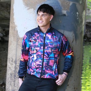 May include: A zip-up jacket with a vibrant cityscape design in shades of pink, blue, and purple. The jacket has black sleeves and a black collar. The text "WESTERN AUTO" is visible on the front.