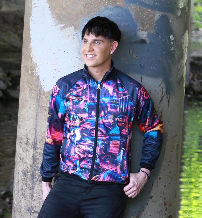 May include: A zip-up jacket with a vibrant cityscape design in shades of pink, blue, and purple. The jacket has black sleeves and a black collar. The text "WESTERN AUTO" is visible on the front.