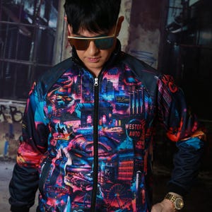 May include: A zip-up track jacket with a vibrant cityscape design in shades of blue, pink, and orange. The jacket features a black collar, sleeves, and a zipper. The words "Western Auto" are visible on the jacket.