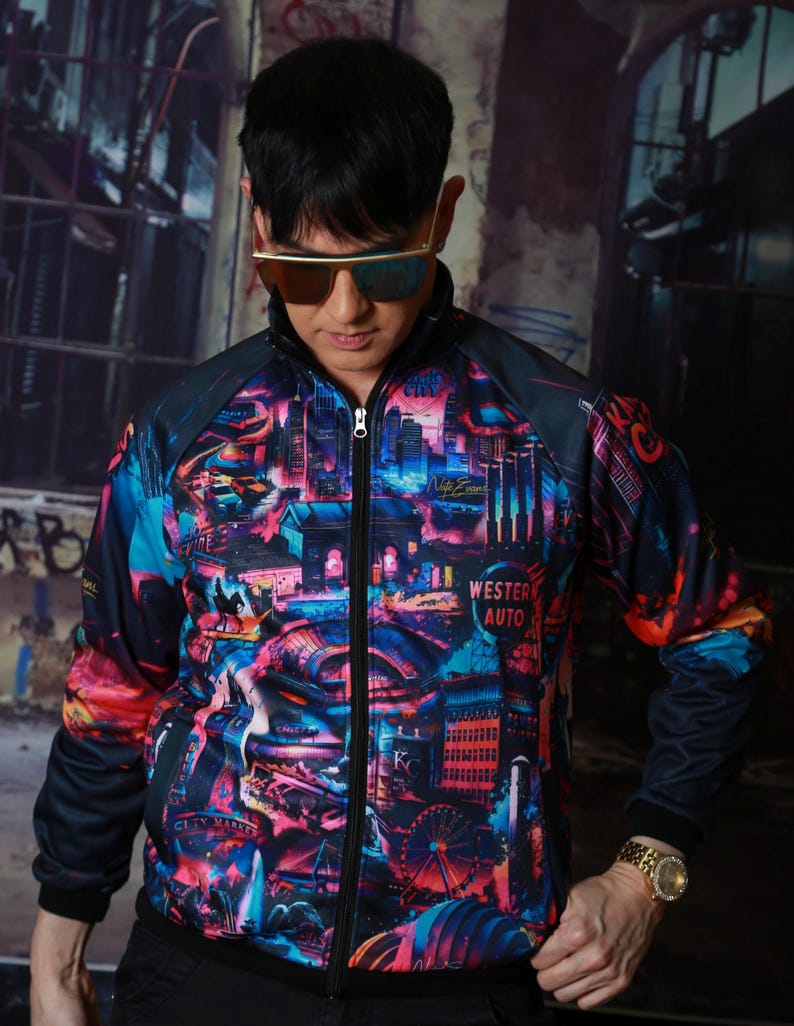 May include: A zip-up track jacket with a vibrant cityscape design in shades of blue, pink, and orange. The jacket features a black collar, sleeves, and a zipper. The words "Western Auto" are visible on the jacket.