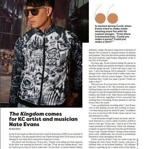 May include: A man wearing a black and white zip-up jacket with a cityscape design, sunglasses, and a silver earring. The jacket features the text "KANSAS CITY" and "WESTERN AUTO". The article is about KC artist and musician Nate Evans.