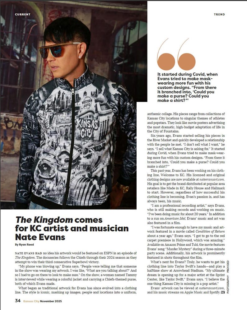 May include: A man wearing a black and white zip-up jacket with a cityscape design, sunglasses, and a silver earring. The jacket features the text "KANSAS CITY" and "WESTERN AUTO". The article is about KC artist and musician Nate Evans.