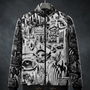 May include: Black and white zip-up jacket featuring a detailed graphic of Kansas City landmarks and the text "Kansas City". The jacket has a stand-up collar, black trim, and the signature "Nate Evans" on the bottom.