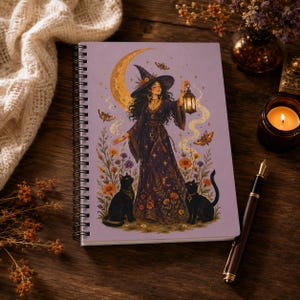 May include: A spiral-bound notebook with a light purple cover featuring a central illustration of a person in a wide-brimmed hat and long dress holding a lantern. The scene includes a large crescent moon, two black cats, moths, and flowers.