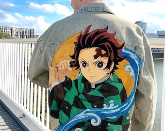 May include: Light-wash denim jacket featuring a vibrant anime-style illustration on the back. The artwork depicts a character with red hair, a green and black patterned outfit, and a dynamic water wave design. The jacket has a classic collar and button closure.