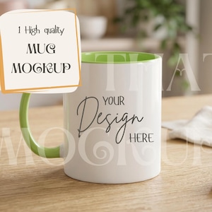 May include: A white mug with a green handle and interior, featuring the text "Your Design Here". The mug is on a wooden surface, with a sign that says "1 High quality MUG MOCKUP".