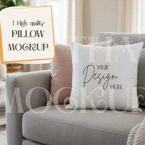 May include: A white square cushion with the text "YOUR Design HERE" on a grey sofa. The cushion is part of a mockup with other cushions in shades of pink and green. The image also includes a sign that says "1 High quality PILLOW MOCKUP".
