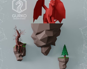Puede incluir: Un dragón rojo de origami se encuentra sobre una roca de origami marrón. Dos rocas de origami más pequeñas con un árbol marrón y un pino verde se encuentran a cada lado del dragón.