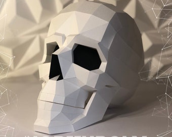 May include: A white papercraft skull with a geometric design. The skull is angled to the right and has a black eye socket.