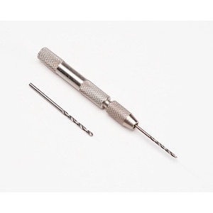 May include: A silver-colored pin vise tool with a textured, knurled grip handle for manual drilling. The tool features a metal collet at the tip holding a thin, spiral-fluted drill bit, with an additional loose drill bit placed nearby.