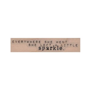 May include: A wooden stamp with the text "Everywhere she went she left a little sparkle."