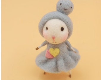 May include: A small, gray felt animal with a heart-shaped patch on its chest. The animal has a round head with a small, smiling face and a gray felt hat.