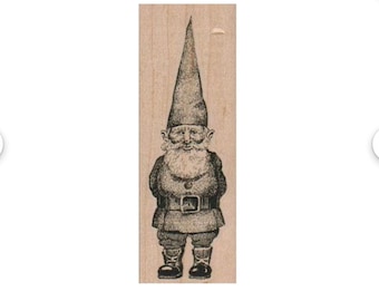 May include: A wood-mounted rubber stamp with a detailed illustration of a garden gnome. The gnome is shown with a long, pointed hat, a full beard, and a belted tunic. Suitable for crafting and scrapbooking projects.