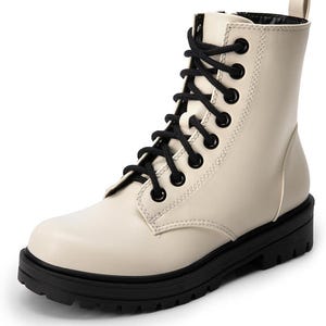 Könnte beinhalten: Cremefarbener Kampfstiefel mit schwarzen Schnürsenkeln und einer schwarzen Profilsohle. Der Stiefel hat eine runde Spitze, eine mittlere Wadenhöhe und eine Zuglasche oben. Die Schnürsenkel verlaufen durch schwarze Ösen. Die Sohle ist dick und robust.