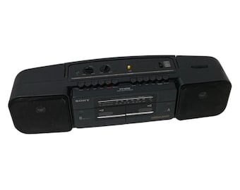 Op de afbeelding: Een zwarte Sony CFS-W300S boombox met geïntegreerde luidsprekers. De stereocassettespeler heeft een radiotuner en een Mega Bass-functie. De boombox heeft een handvat voor gemakkelijk dragen.