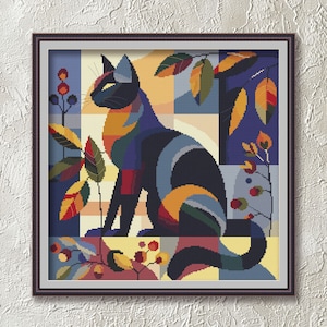 Op de afbeelding: Een vierkant ingelijste kruissteekborduurwerk met een gestileerde kat in profiel. De kat is opgebouwd uit geometrische kleurblokken in marineblauw, geel, rood en groenblauw. Het is omringd door abstract gebladerte, bessen en een rasterpatroon.