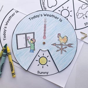 May include: A colorful weather wheel with the text "Today's Weather Is" and illustrations of weather conditions. Includes a thermometer, a rooster weather vane, and a child drawing a heart on a window. Crayons are visible.
