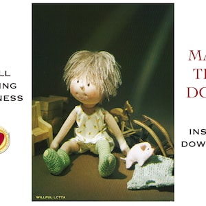 May include: A handmade doll with blonde hair, wearing a white and yellow dress and green knitted booties. The doll is sitting on a brown surface with a small pink pig and a knitted blanket.