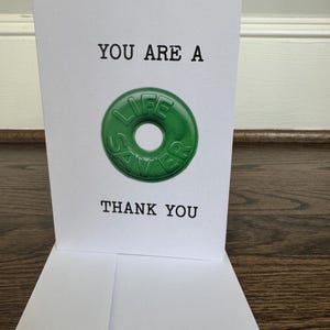K&ouml;nnte beinhalten: Eine wei&szlig;e Karte mit schwarzem Text, der "You are a Life Saver. Thank You." lautet. Auf der Karte ist ein gr&uuml;nes Life Saver Bonbon abgebildet.