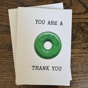 K&ouml;nnte beinhalten: Eine wei&szlig;e Karte mit dem Text "You are a" und einem gr&uuml;nen Life Saver Bonbon. Der Text "Thank You" befindet sich unter dem Bonbon.