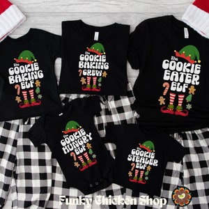 May include: A set of five black t-shirts with a Christmas elf design and the text "The Cookie Baking Elf", "The Cookie Baking Crew", "The Cookie Eater Elf", "The Cookie Hungry Elf", and "The Cookie Stealer Elf".