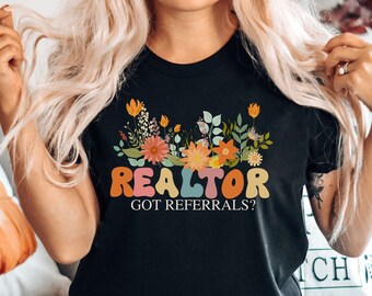 May include: Black t-shirt with a floral design and the text "Realtor Got Referrals?" in colorful, retro-style lettering.