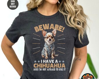 May include: Dark grey heather t-shirt with the text "BEWARE! I HAVE A CHIHUAHUA AND I'M NOT AFRAID TO USE IT". The graphic features a Chihuahua wearing a denim jacket. The shirt is from Funky Chicken Shop.