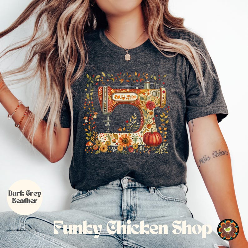 May include: Dark grey heather t-shirt featuring a colorful sewing machine design. The sewing machine is decorated with floral and pumpkin motifs. The shirt also has the text "Funky Chicken Shop".