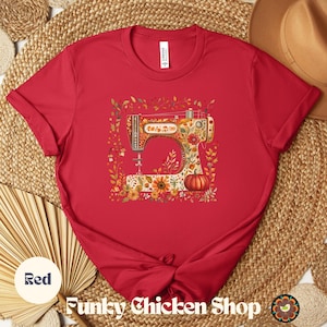 May include: A red t-shirt featuring a colorful illustration of a vintage sewing machine adorned with floral and pumpkin motifs. The shirt has short sleeves and a crew neck. The text "Funky Chicken Shop" is at the bottom.