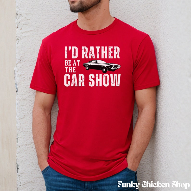 Peut inclure: T-shirt rouge avec un graphisme blanc qui dit "J'aimerais mieux &ecirc;tre au salon de l'auto" avec une image en noir et blanc d'une voiture classique.