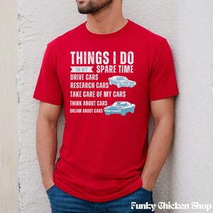 以下が含まれることがあります： 「THINGS I DO IN MY SPARE TIME」というテキストと、車に関連する活動のリストが書かれた赤いTシャツ。テキストは白で、Tシャツには青い車のイラストが2つ描かれている。