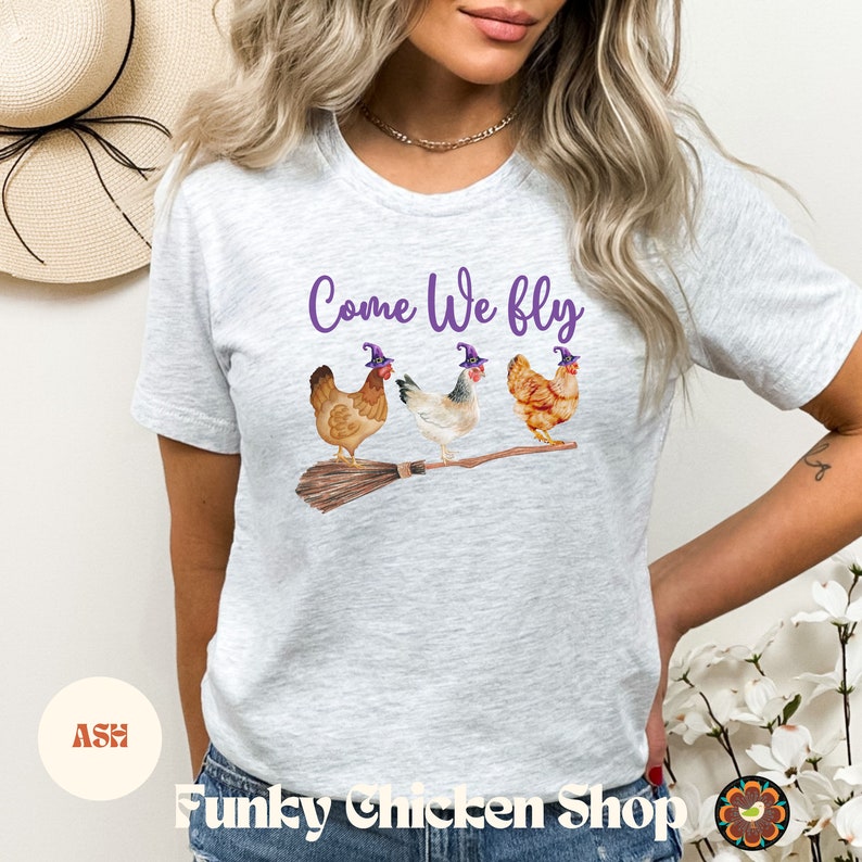 May include: A grey t-shirt with the text "Come We Fly" and a graphic of three chickens wearing witch hats and riding a broomstick.