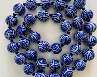 May include: A blue and white porcelain bead necklace with a repeating pattern of Chinese characters. The beads are strung on a dark blue cord.
