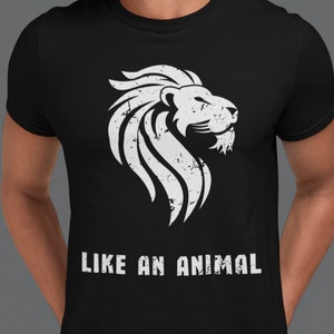 K&ouml;nnte beinhalten: Schwarzes T-Shirt mit einem wei&szlig;en L&ouml;wen-Motiv und dem Aufdruck "LIKE AN ANIMAL" auf der Vorderseite.
