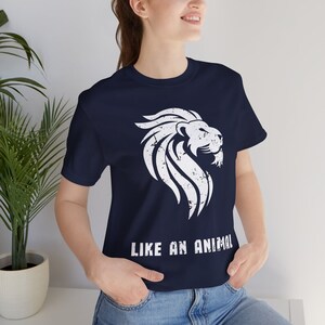 K&ouml;nnte beinhalten: Ein marineblaues T-Shirt mit einem wei&szlig;en, abgenutzten L&ouml;wenmotiv und dem Text "LIKE AN ANIMAL" auf der Vorderseite.
